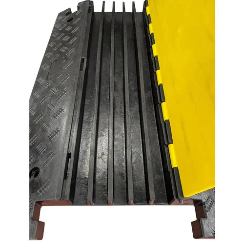 Five deep cable channels with the yellow lid swung fully open, chequer-tread wing left, rust-marked steel base rails below