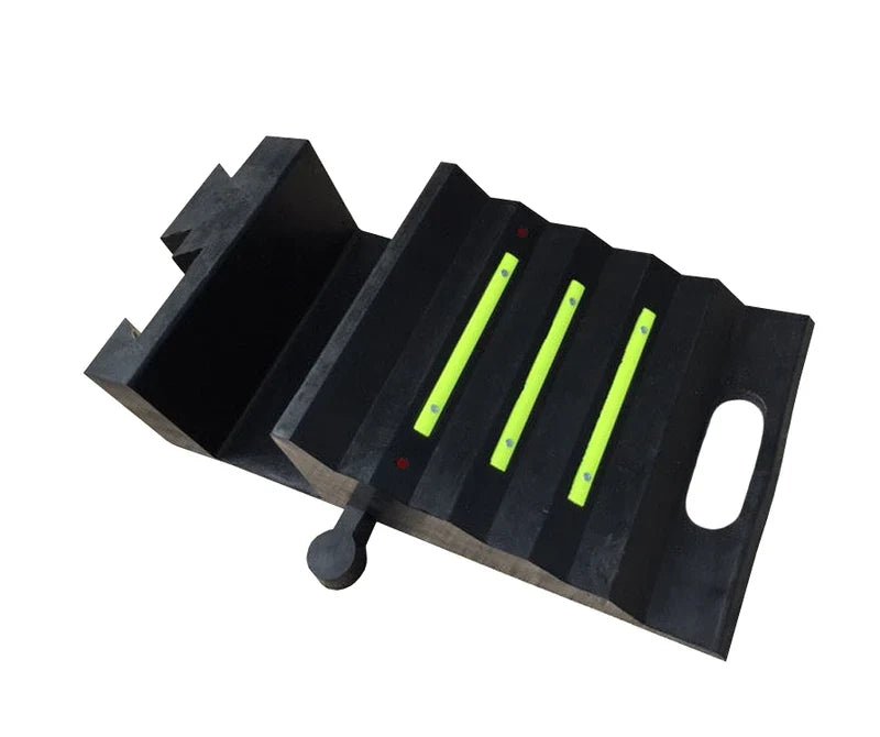 Angled shot of the black rubber ramp portion, three yellow strips on ribbed tread, oval handle slot and round peg