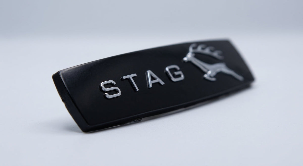 Black gloss STAG side badge with stag emblem on the right, angled studio shot