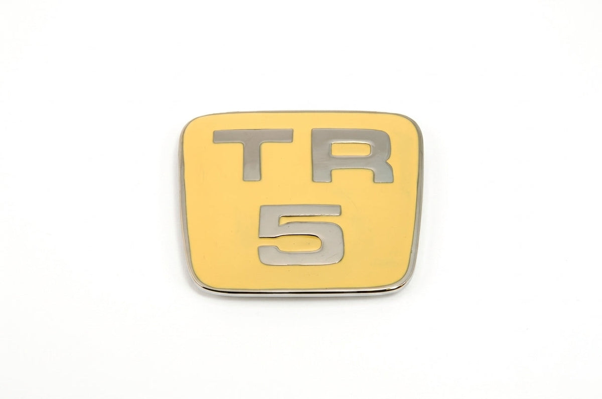 Gold enamelled TR5 bonnet badge with chrome trim, studio shot on white