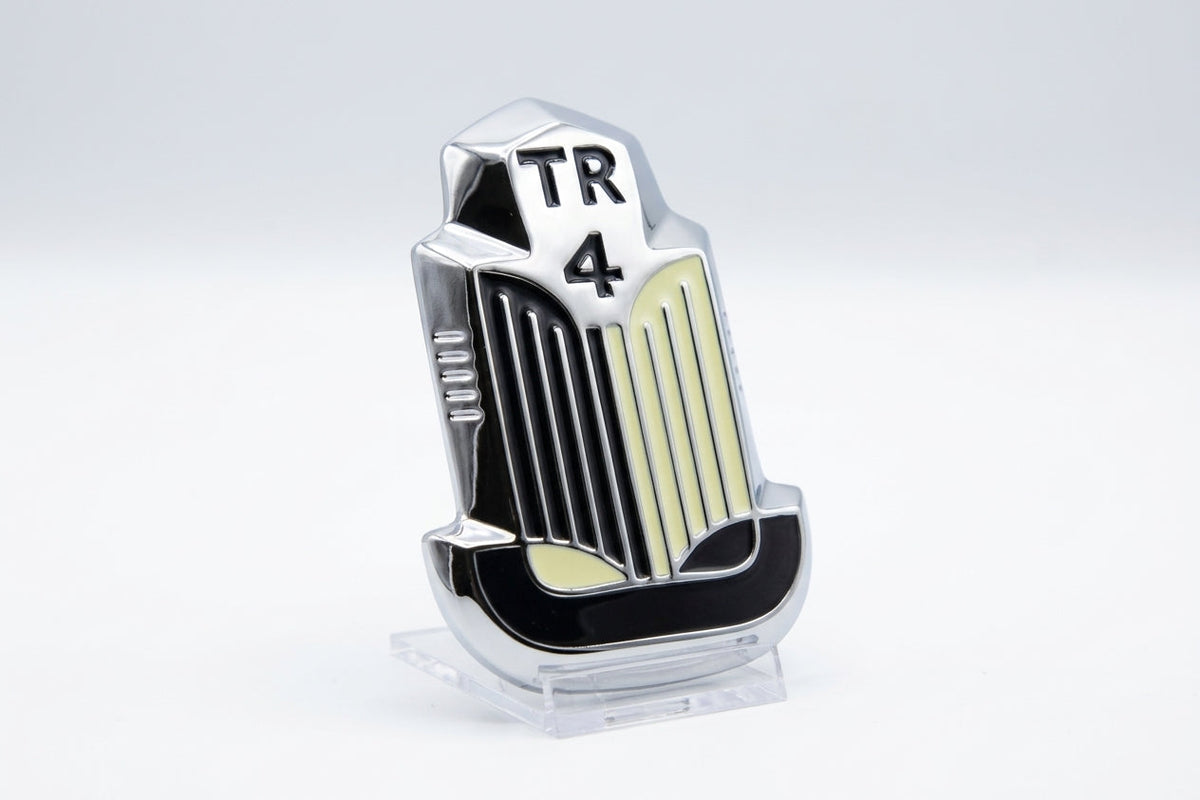 Chrome TR4 bonnet badge with cream and black enamel, studio shot on white