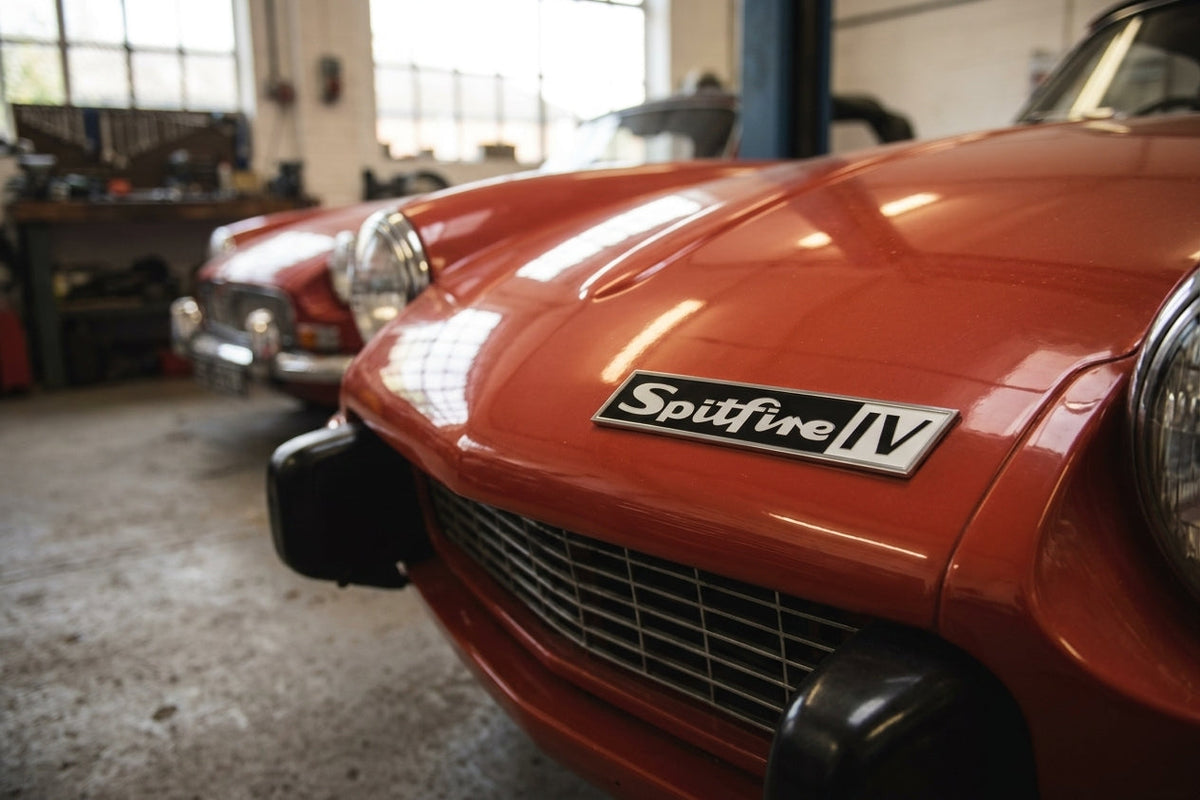 Spitfire IV badge fitted to an orange Spitfire's bonnet in a workshop