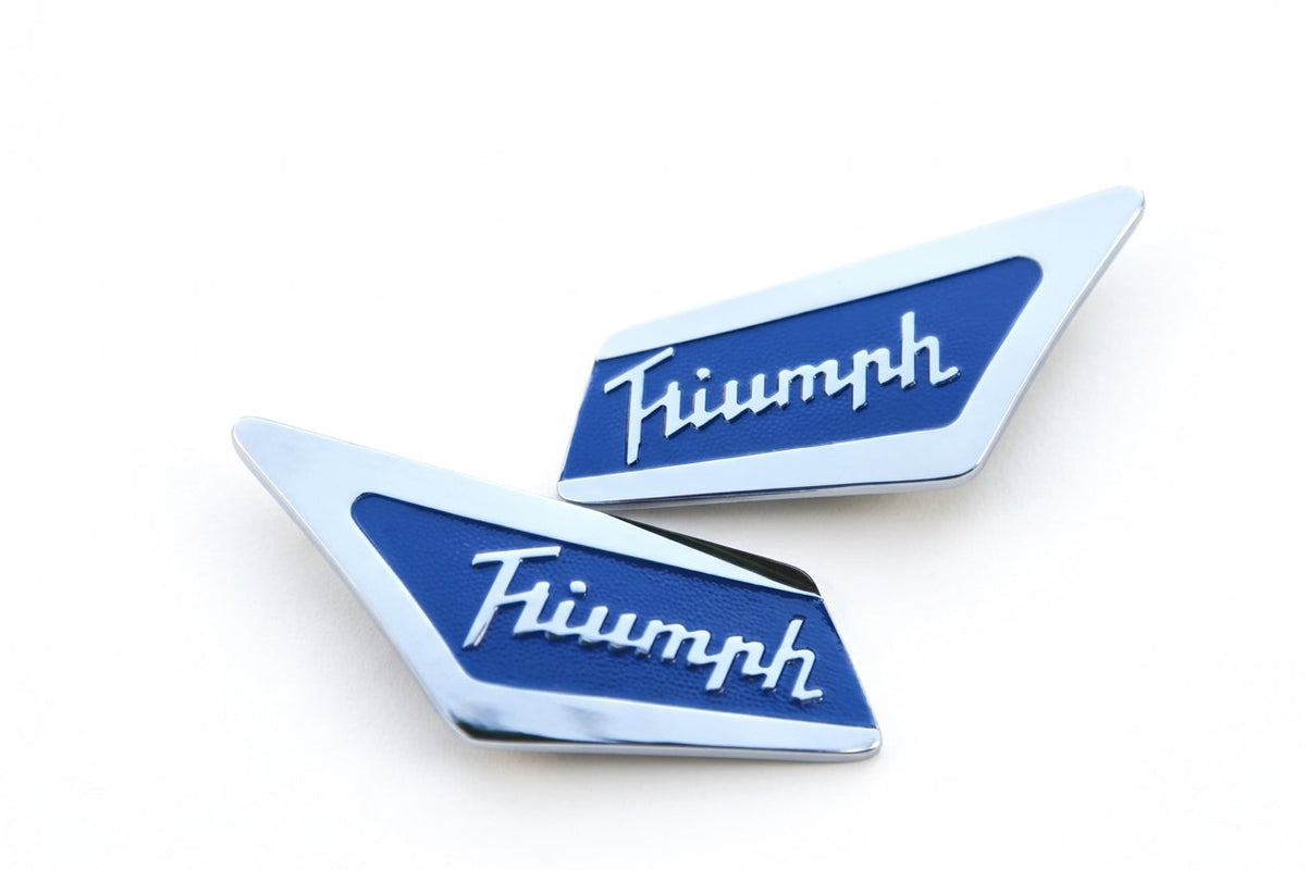 Pair of blue and chrome Triumph script pillar badges, studio white background