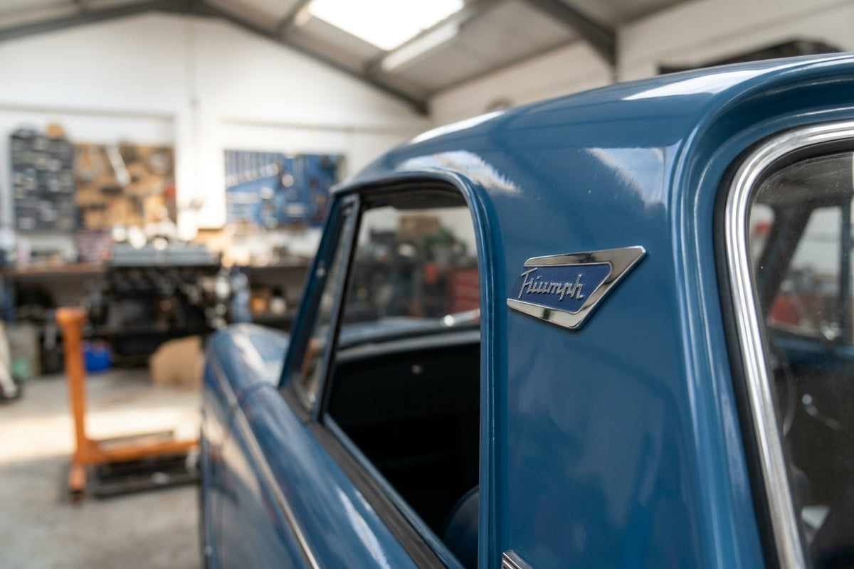 Blue and chrome Triumph pillar badge fitted to a blue car's roof pillar