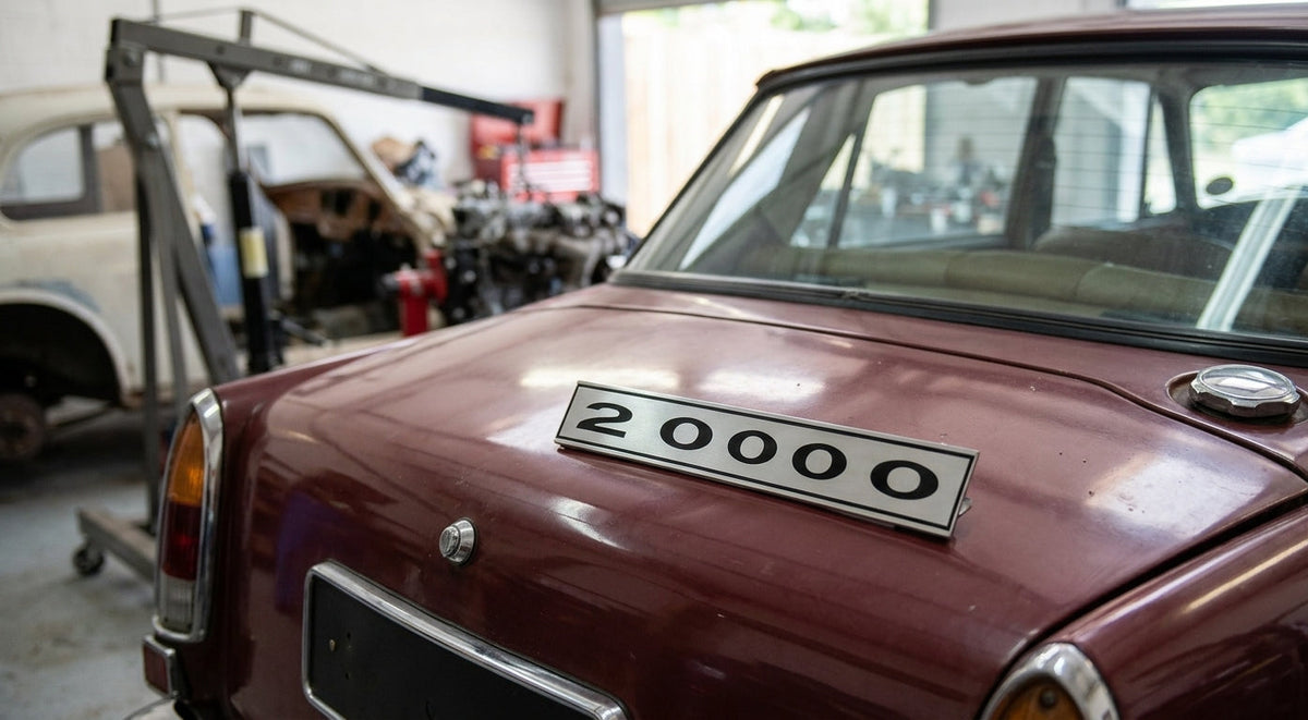 2000 badge fitted to the boot lid of a maroon classic car in a garage