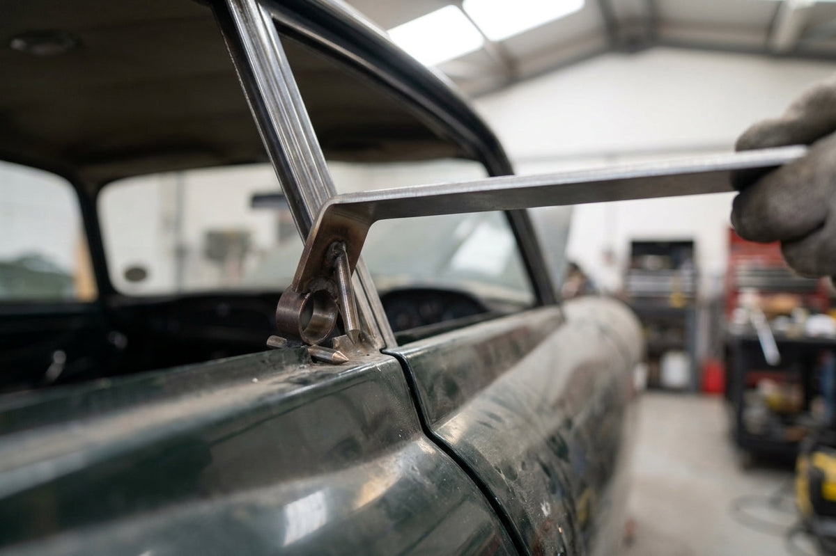 Metal fitting tool being used to press trim onto a car window frame