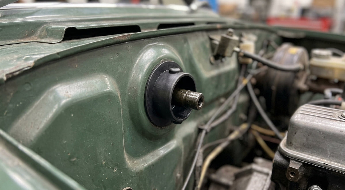 Black steering column bush fitted through the firewall of a green Triumph Stag