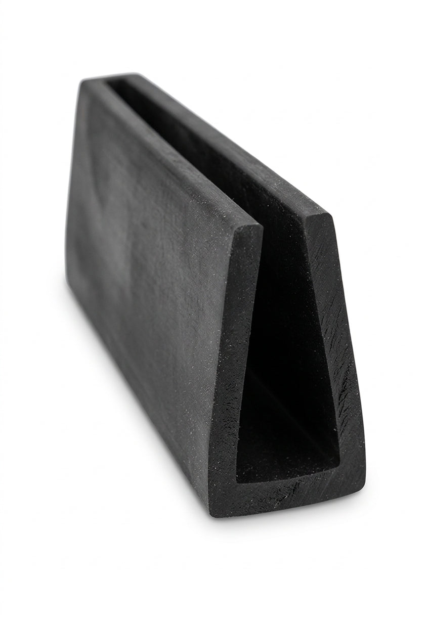 Black EPDM U-channel profile standing at an angle, plain white background shot of square block