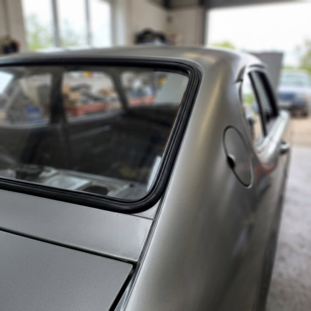 Black windscreen seal fitted around a silver Capri's rear side window, workshop