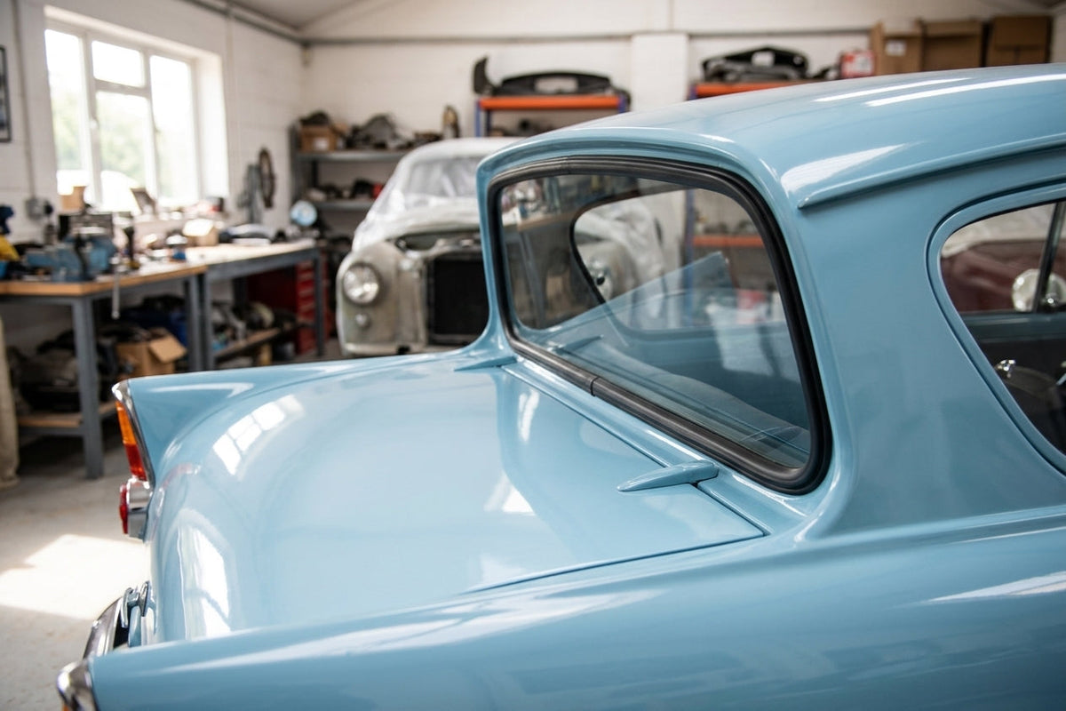 Black windscreen seal fitted to a pale blue Anglia's rear window corner, workshop