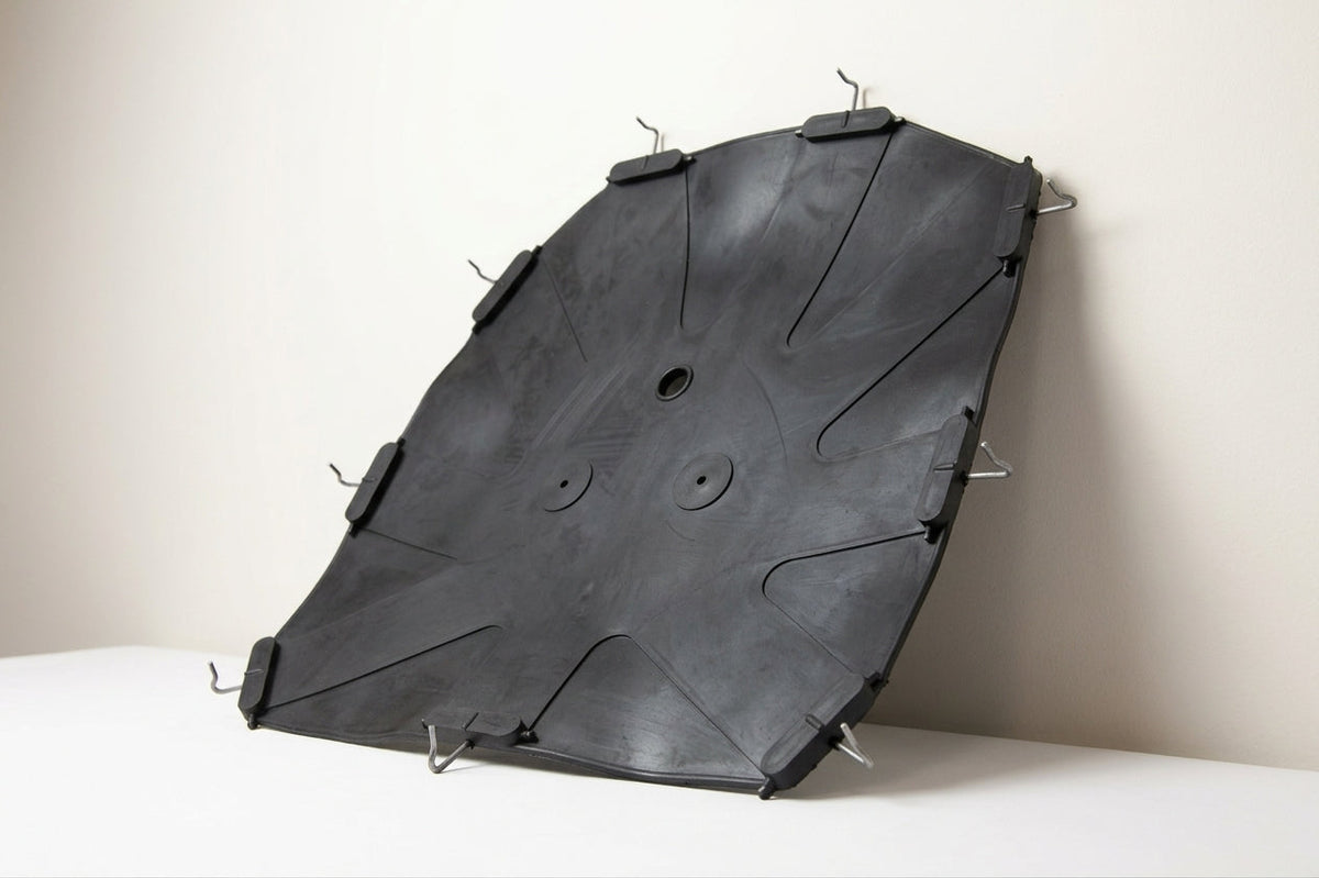 Black moulded seat diaphragm with metal hooks, leaning against a studio wall