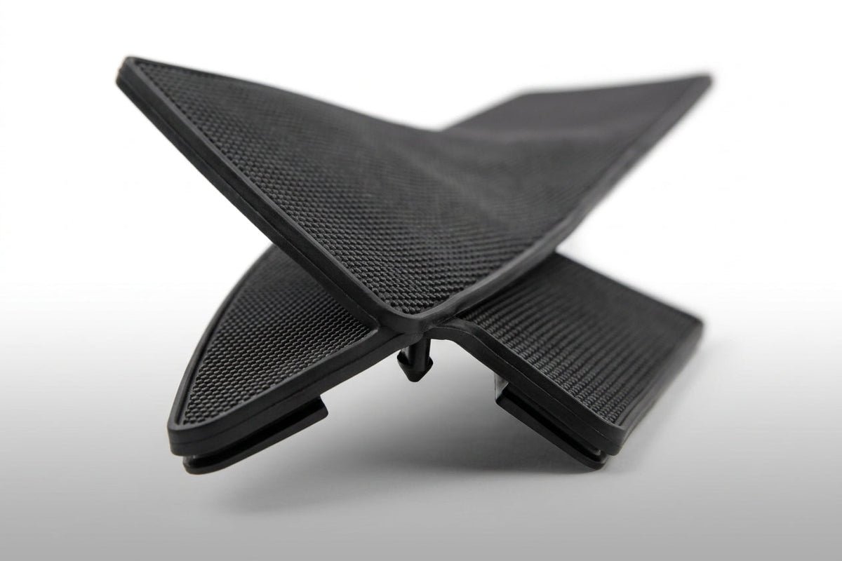 Black textured rubber dashboard pad shown folded in a cross shape, studio shot