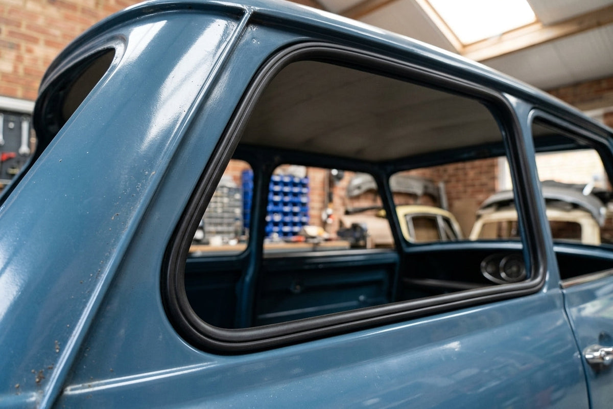 Black rubber seal fitted around the rear side window of a blue classic Mini