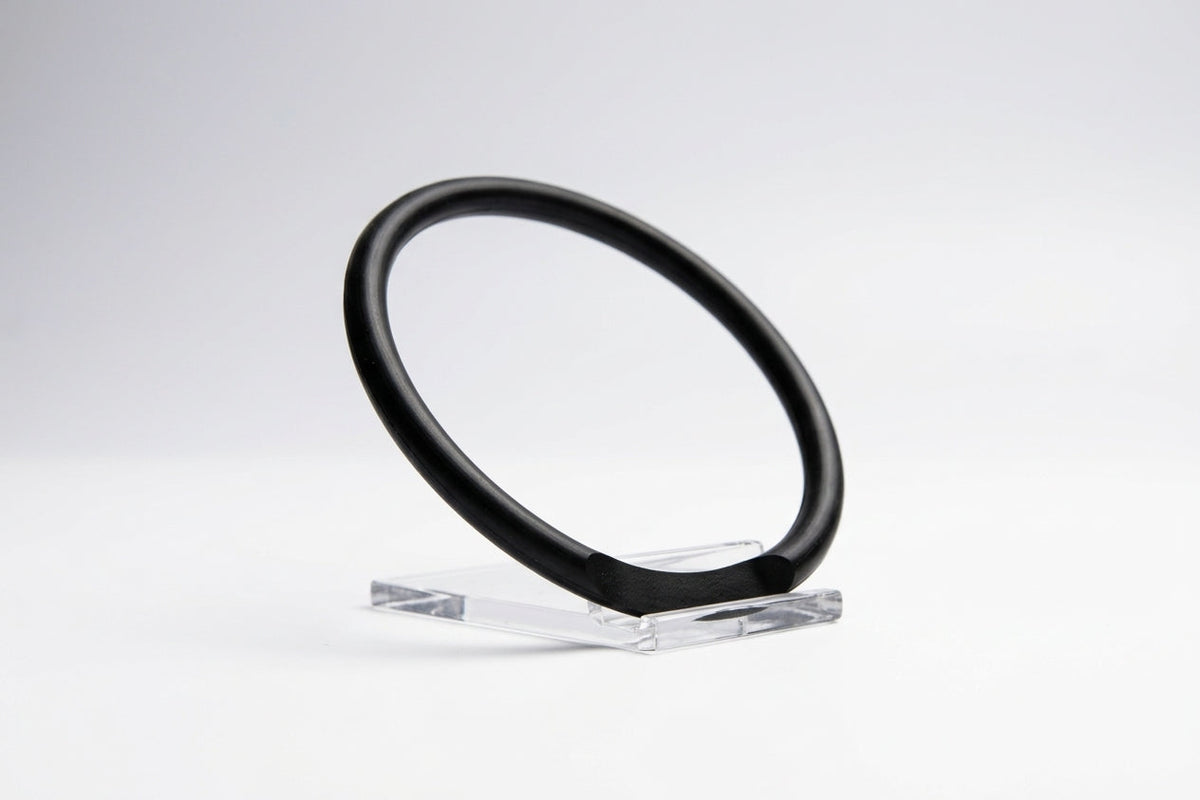 Black nitrile O-ring on a clear stand, slightly flattened where it rests