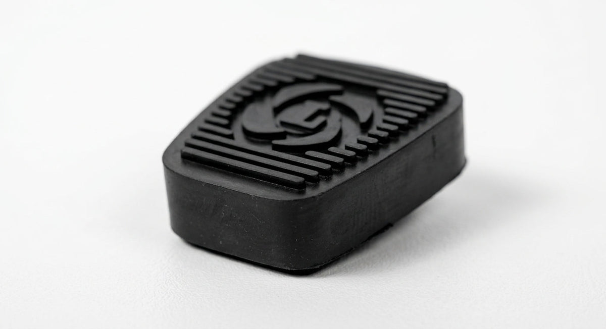 Black ribbed rubber pedal pad with embossed logo, studio shot on white