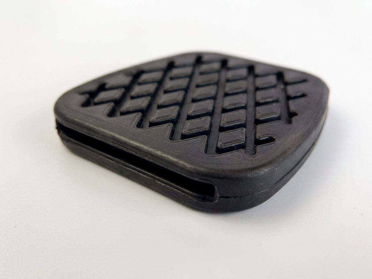Black rubber pedal pad with a diamond cross-hatch tread, studio shot