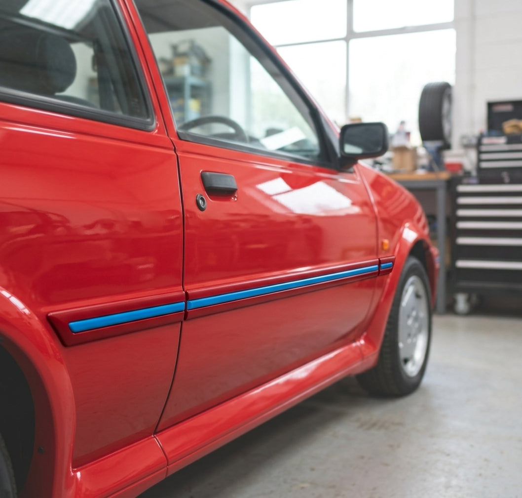 Black moulding with a blue stripe across the mid-door of a red Fiesta, car facing right in a garage