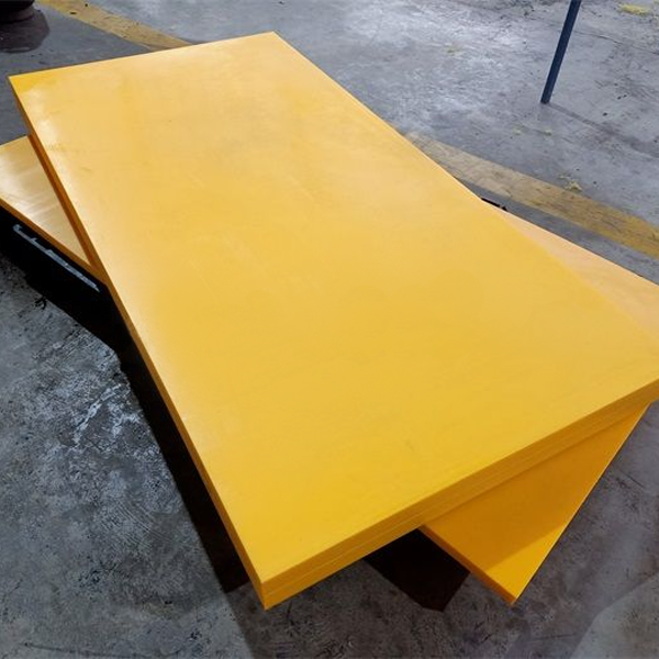 Two large yellow polyethylene sheets resting on a black frame on a concrete workshop floor