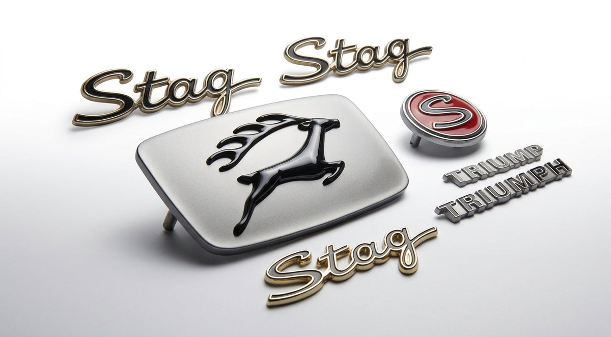 Flat lay of Triumph Stag Mk1 badge set: leaping stag grille badge, script badges and TRIUMPH badge
