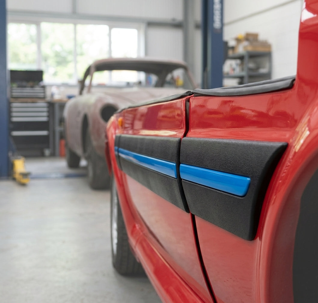 Black moulding with a blue stripe on the rear wing of a red car, workshop with a bare shell behind