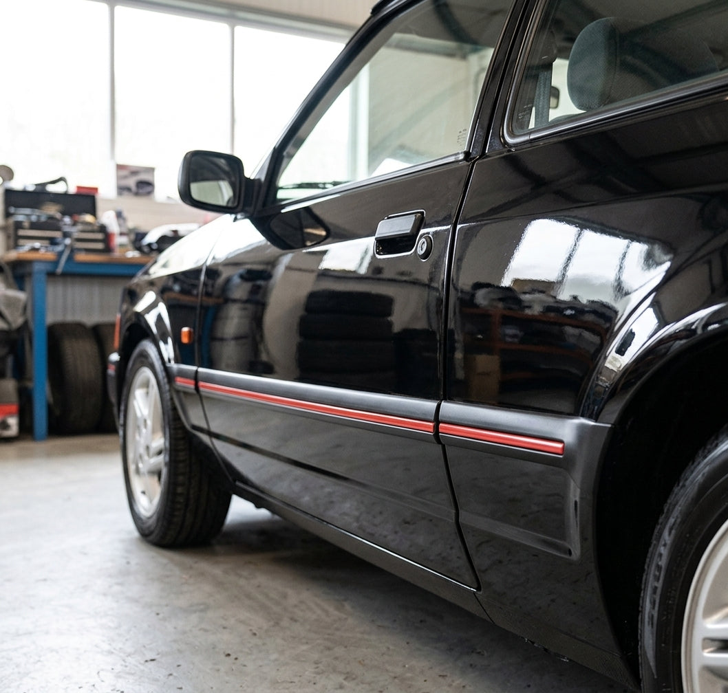 Black door mouldings with red insert stripe fitted along a black Escort's sill