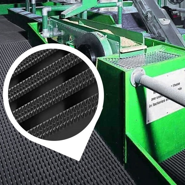 Close-up of a black, heavy-duty industrial matting roll laid beneath bright green industrial conveyor or processing machinery. The mat's surface is visible and wet, demonstrating its use in industrial wet areas. An inset circle magnifies the mat's non-slip, high-traction surface with UV-resistant diamond-patterned ribs, confirming its durability for industrial and outdoor use.