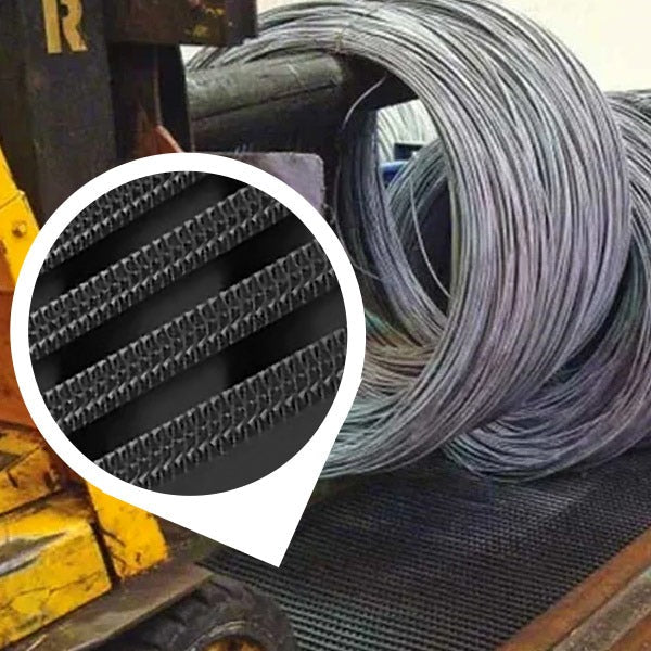 Close-up of a black, heavy-duty industrial matting roll on a factory floor next to large coils of metal wire and yellow machinery. An inset circle provides a magnified view of the mat's non-slip, high-traction surface, featuring UV-resistant diamond-patterned ribs, ideal for industrial wet areas and heavy object placement.