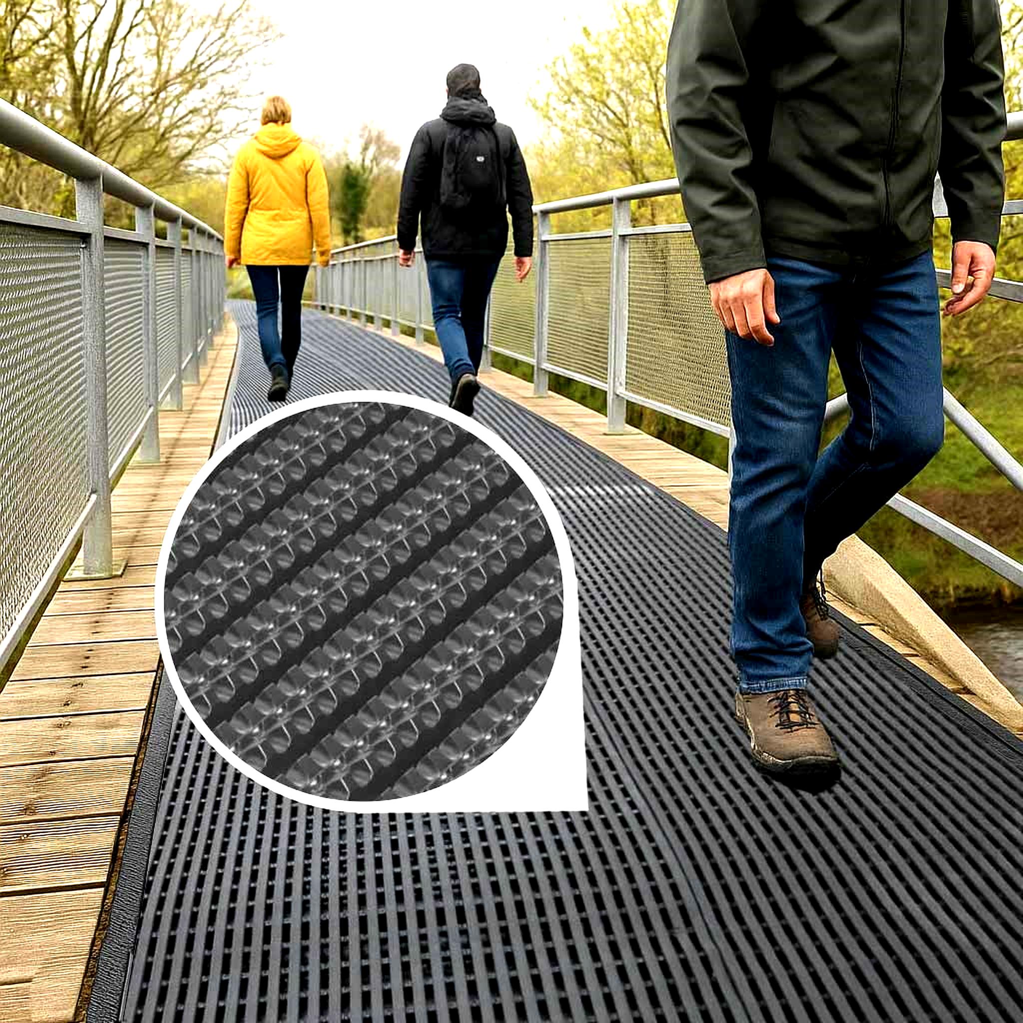 Heavy-duty black rubber Anti-Fatigue Anti-Slip Wet Area Mat installed on an outdoor wooden and metal bridge, providing slip-resistant and comfort flooring. The inset circle shows a close-up of the mat's textured surface and drainage holes, ideal for kitchens, workplaces, and wet environments.