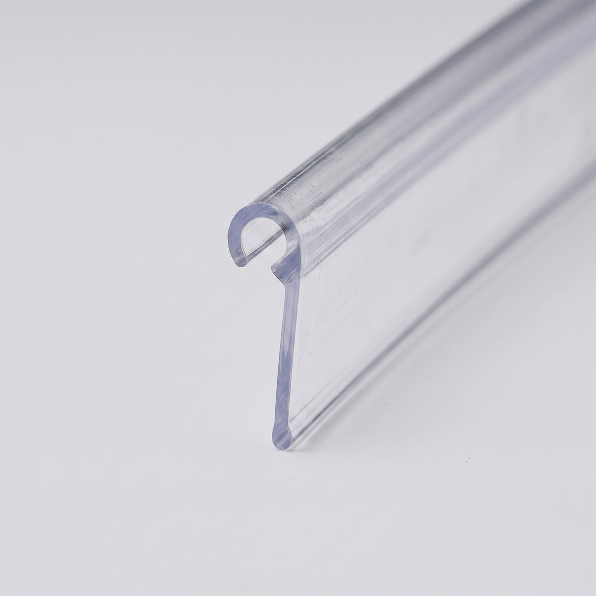 Clear rigid PVC hook-over seal length on white, curled hook along one edge and a flat sealing blade