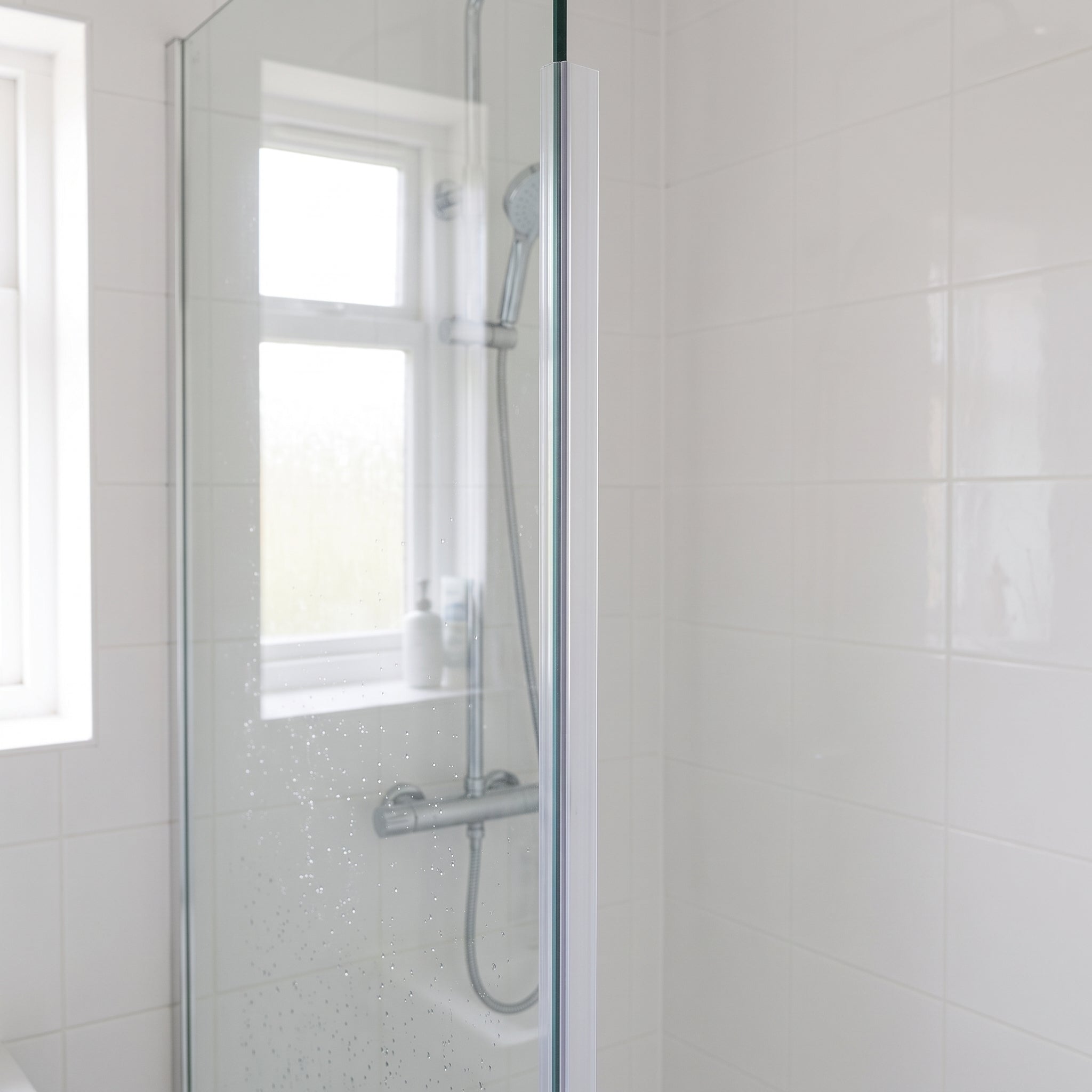 Clear FIN012 vertical seal on a shower screen upright - fin pressing against the tiled wall for the full height