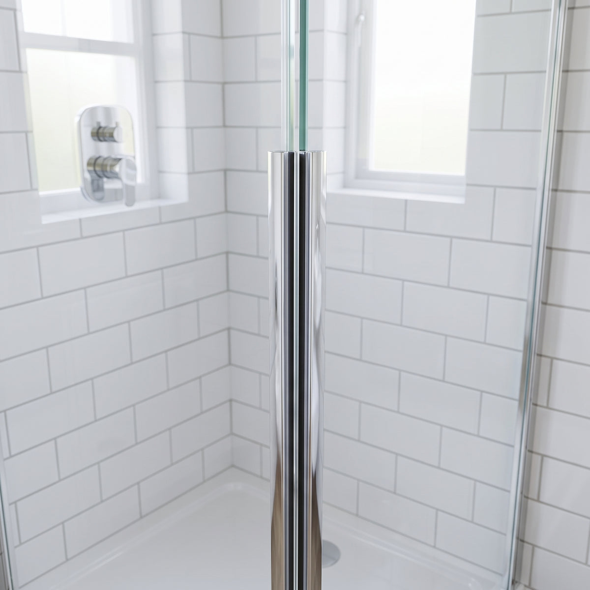 Bright chrome seal running full height where shower glass meets, white metro tiles and chrome valve behind