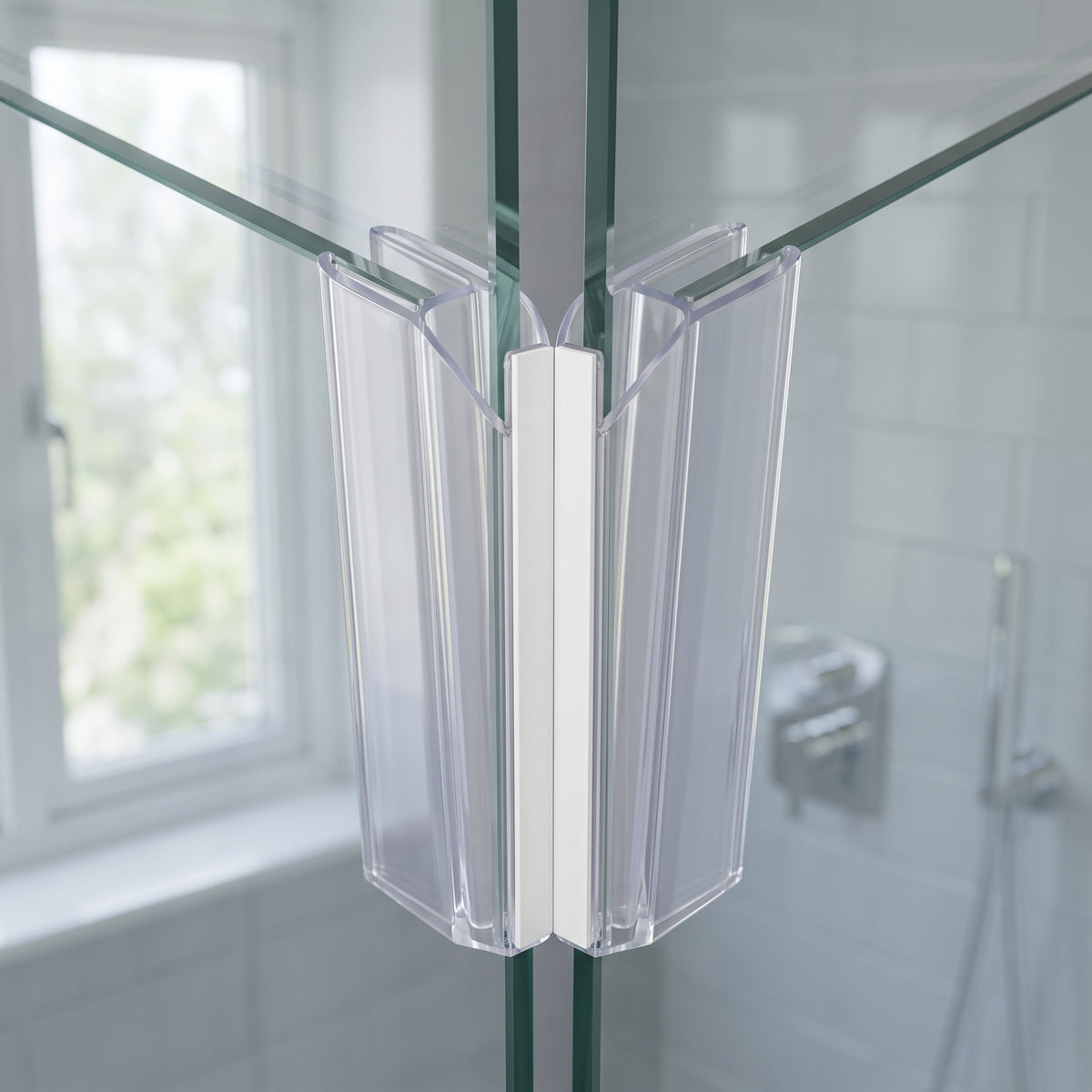 Two clear seals with a white magnet strip meeting where glass shower panels close at a corner