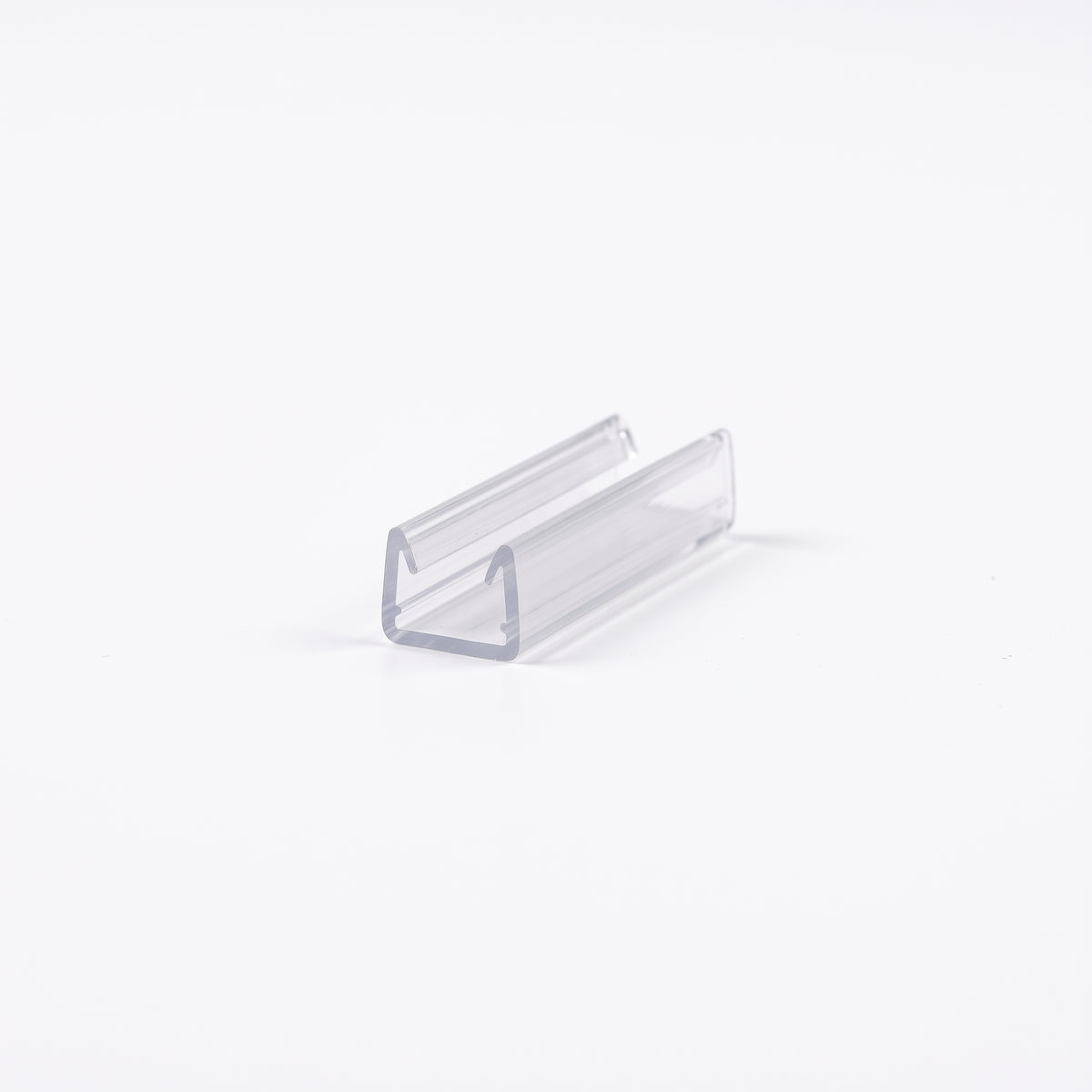 Short offcut of clear U-channel seal lying at an angle on a white background, open channel facing up
