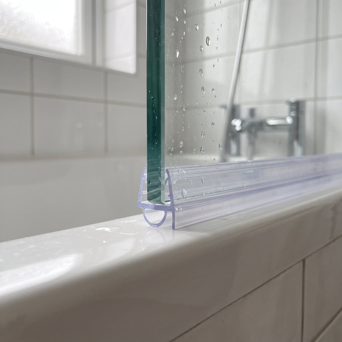 Clear seal on a bath screen bottom edge, small bubble squashed against the white bath rim