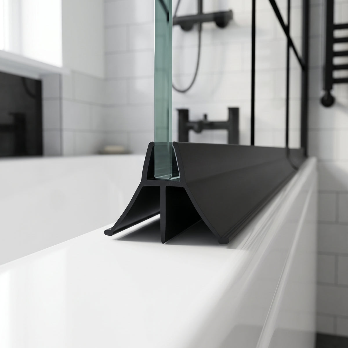 Black seal on a glass bath screen edge, wide fin sweeping onto the white bath rim, black shower fittings behind