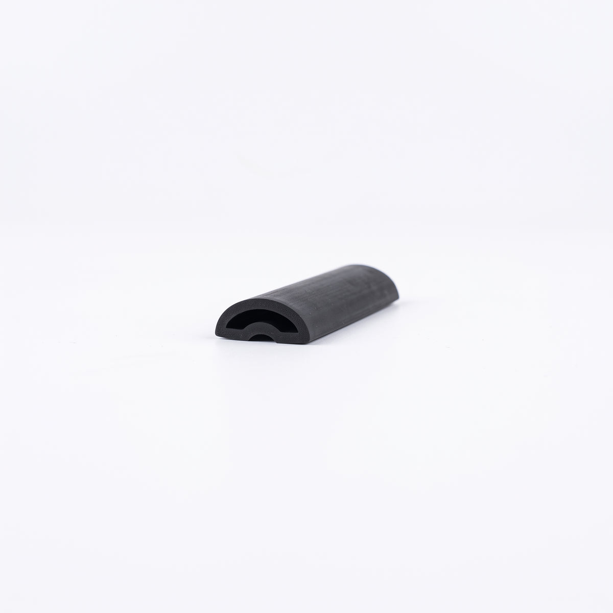 Short offcut of black rubber threshold seal on white, domed top with a hollow arch at the cut end