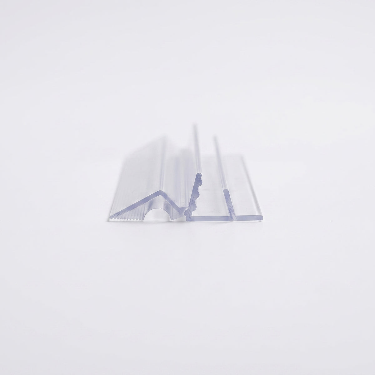 Short offcut of clear bath screen seal on white, showing the glass channel, ribbed grip fin and angled deflector