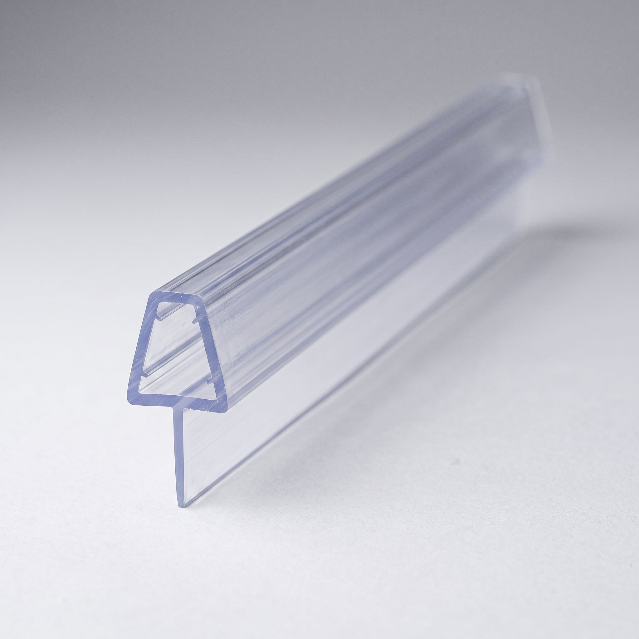 Studio shot of the tapered shower seal profile - clear PVC U-channel with soft fin tapering from 20mm to 5mm along its 900mm length