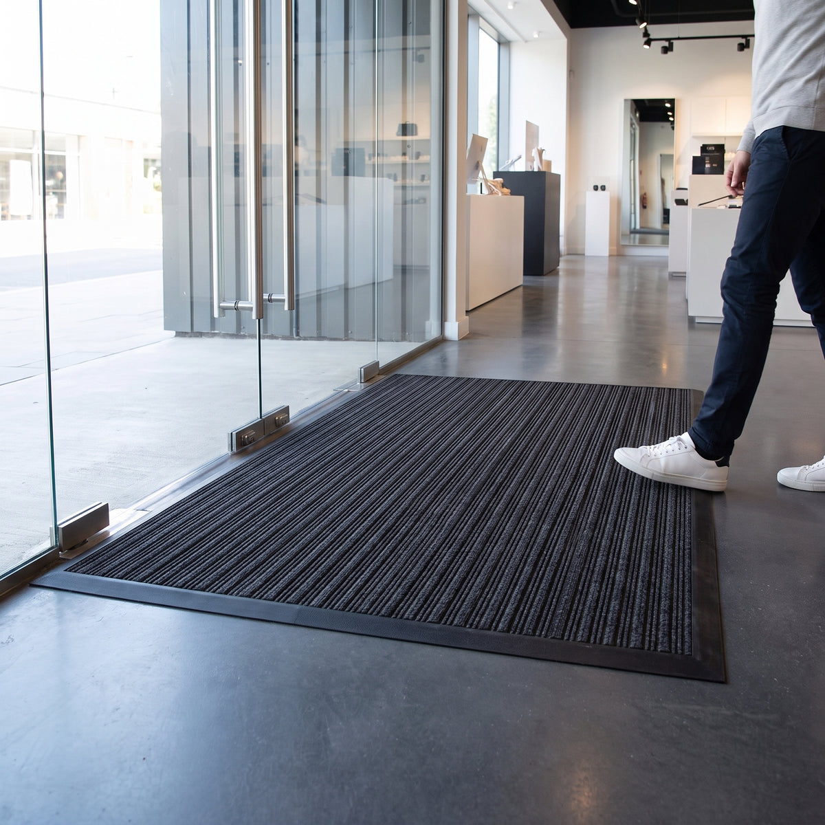 Black entrance mat with carpet inserts laid inside the glass doors of a modern retail store