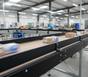 Black side rails on parcel conveyors in a bright warehouse, boxes and packs moving along the belts