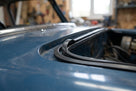 Black rectangular rubber strip fitted around a rear door aperture of a blue Mini van