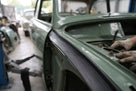 Rectangular rubber strip fitted along a green classic car body seam during restoration