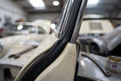 Black rubber strip fitted beside chrome trim on a cream classic car's windscreen pillar