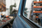 Black rectangular rubber strip fitted beside chrome trim on a blue classic car pillar