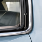 Wire glazing strip fitting tool inserted into a light blue classic car's window trim