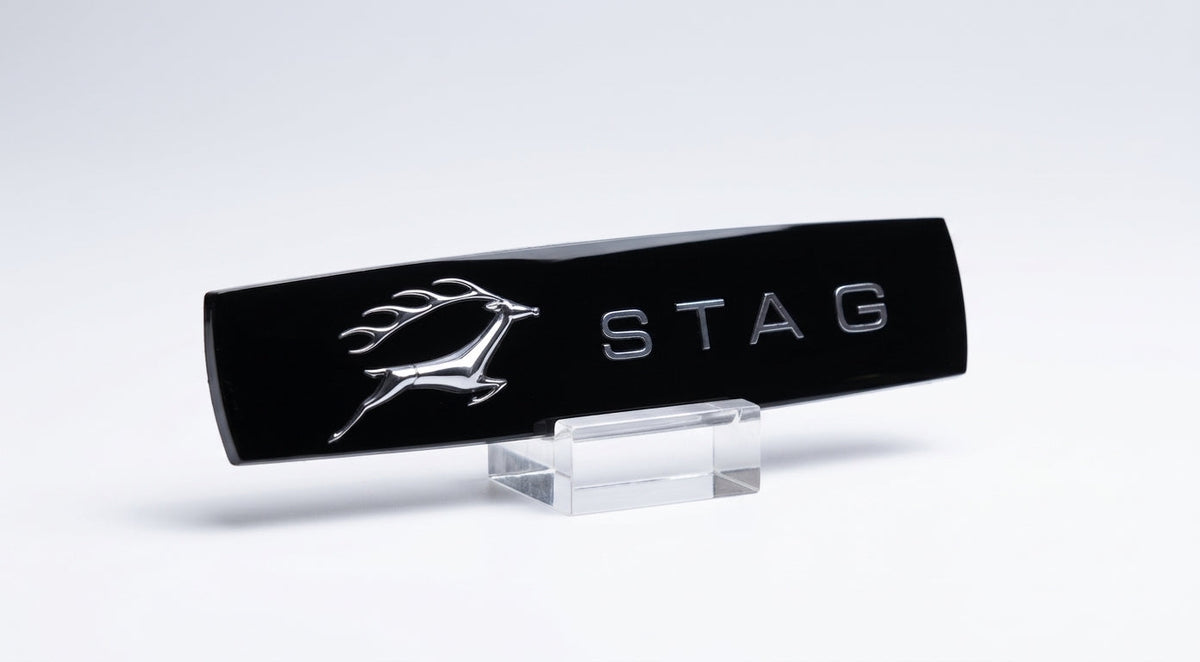 Black gloss STAG side badge with chrome leaping stag, propped on a clear stand