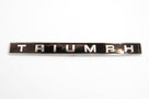 Chrome TRIUMPH badge shown alone on a plain studio background