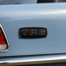Black TR6 grill badge fitted to the boot of a light blue Triumph, close-up