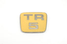 Gold enamelled TR5 bonnet badge with chrome trim, studio shot on white