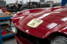TR5 bonnet badge fitted to a red Triumph's bonnet, close-up